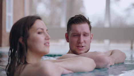 adult-man-and-woman-are-lying-in-swimming-pool-relaxing-and-chatting-cheerfully-wellness-center